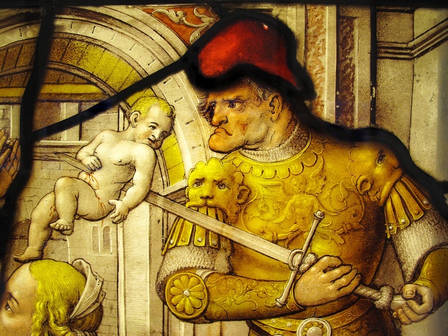 London, UK - December 10, 2010 : The Massacre Of The Innocents from the New Testament shown in an image on a medieval 16th century stained glass window panel. The image shows a Roman soldier slaughtering a boy child on the orders of Herod, in an attempt t